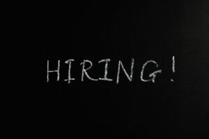 Close-up of the word 'Hiring!' written in white chalk on a blackboard, ideal for recruitment themes.