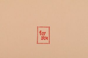 Simple 'For You' text in red on blank pink paper background. Perfect for personalization.